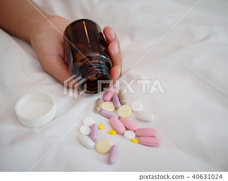Closeup woman hand lying on the bed with pills.  40631024