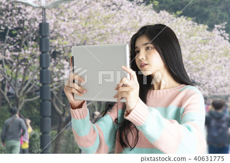 Girl taking photo of blooming flower with tablet. 40631775