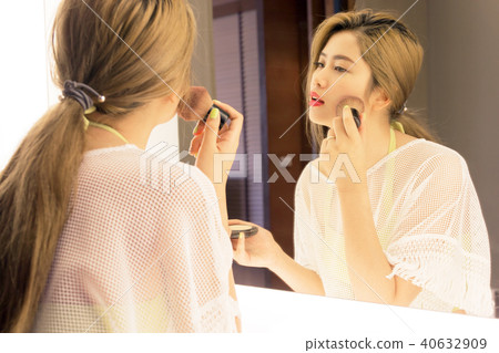 Beautiful Asian teenage girl applying powder her cheek before th 40632909