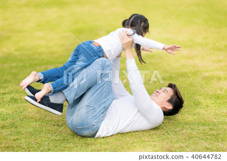 Dad is playing with him daughter in the park. 40644782