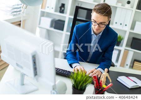 A young man is working at the computer in the office. A young man is working at the computer in the office. 40648424