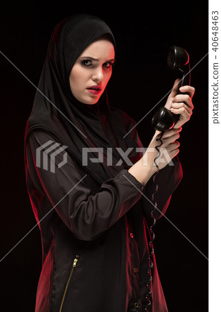 Portrait of beautiful serious scared young muslim woman wearing black hijab calling for help on 40648463