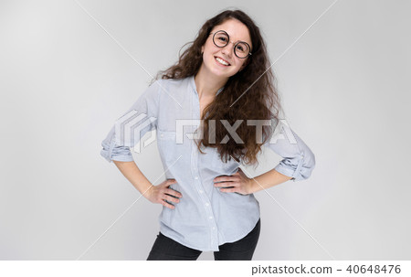 Portrait of a happy young girl in glasses. Beautiful young girl on a gray background. A young girl 40648476