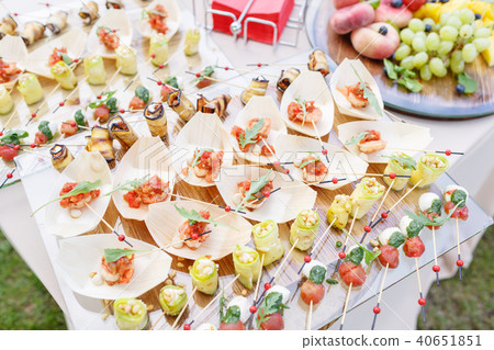 Delicious shrimp and sliced tomatoes on a wooden boat. Zucchini rolls with pine nuts. Tasty buffet 40651851