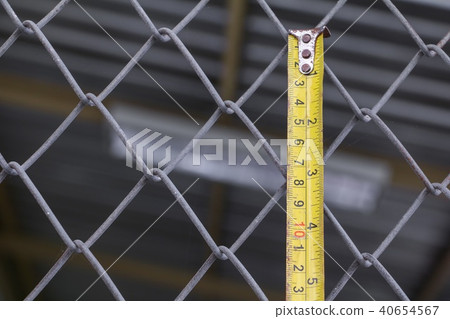 tape measure yellow on wire mesh cage  40654567