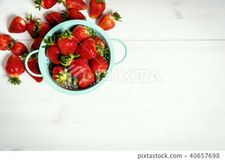red strawberries in colander on a white wooden table 40657698