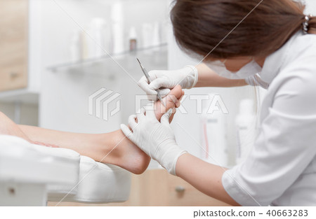 Doctor making cleaning procedure client foot with special iron tool. Doctor making cleaning procedure client foot with special iron tool. 40663283