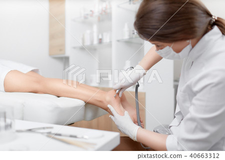 Woman relaxing at beauty salon, when podiatrist making procedure for feet. Woman relaxing at beauty salon, when podiatrist making procedure for feet. 40663312