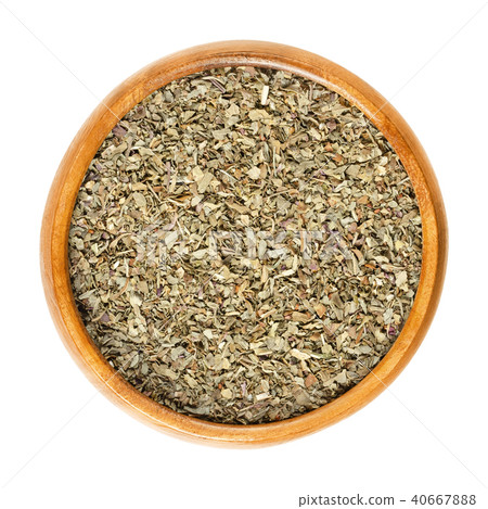 Dried basil leaves in wooden bowl over white 40667888