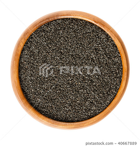 Dried basil seeds in wooden bowl over white Dried basil seeds in wooden bowl over white 40667889