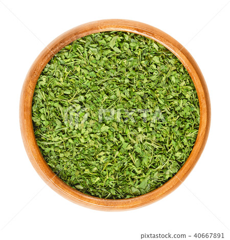 Dried parsley in wooden bowl over white 40667891