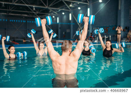 Class with trainer on workout with aqua dumbbells 40668967