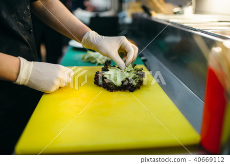 Male cook prepares fresh salad for burger 40669112