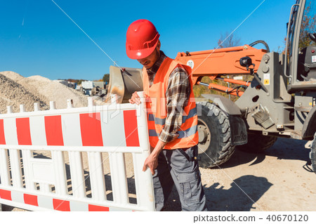 Worker setting up earthworks construction site 40670120