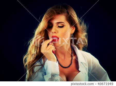 Woman eating berry. Pin up girl wearing unbuttoned blouse and bra. 40671949