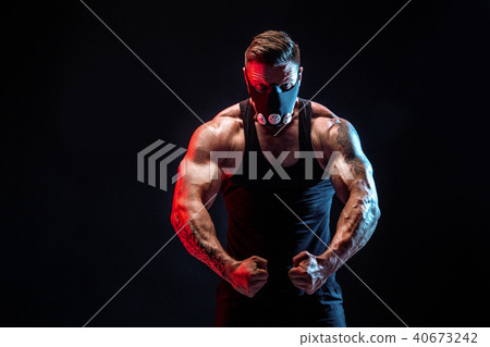 Strong male athlete in a black training mask on a black background Strong male athlete in a black training mask on a black background 40673242