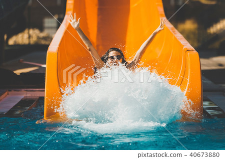 joyful woman going down by the slide in aqua park 40673880
