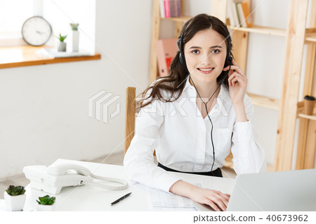 Young friendly operator woman agent or business woman with headsets working in a call centre. Young friendly operator woman agent or business woman with headsets working in a call centre. 40673962