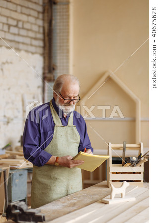old shop teaher is sketching with pencil and notepad near the table old shop teaher is sketching with pencil and notepad near the table 40675628