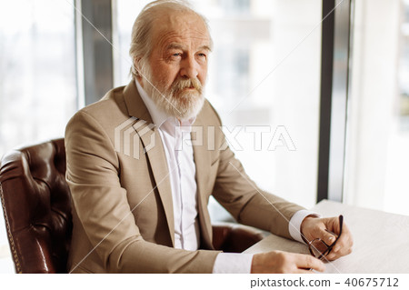 close up portrait of attractive old leader sitting at workplace 40675712