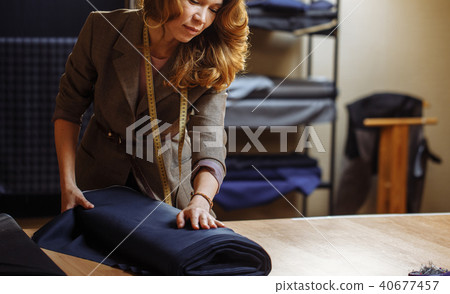 Female tailor choosing fabric for pattern cutting. Men's Wear industry, tailoring process Concept 40677457