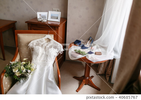 white wedding dress with lace lying on the chair. bouquet different flowers. Modern bridal bunch 40685767