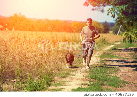 A man with a dog walks along a rural road 40687189
