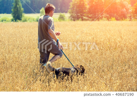 Man with dog running in an oat field in summer 40687190