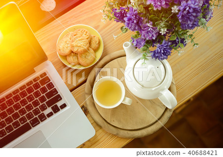 cup, tea pot ,cookies and laptop on wooden desk cup, tea pot ,cookies and laptop on wooden desk 40688421