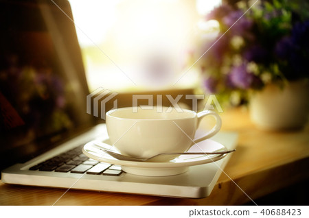 Cup of coffee and laptop on wooden table. Cup of coffee and laptop on wooden table. 40688423