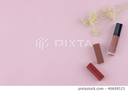 Lipsticks and lip gloss with white dried flowers 40689525