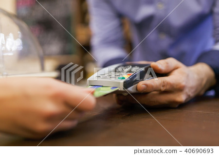 Image of buyer with bank card and seller with terminal in hand Image of buyer with bank card and seller with terminal in hand 40690693