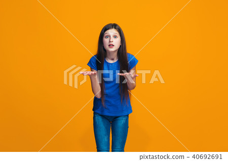Beautiful female half-length portrait on orange studio backgroud. The young emotional teen girl 40692691