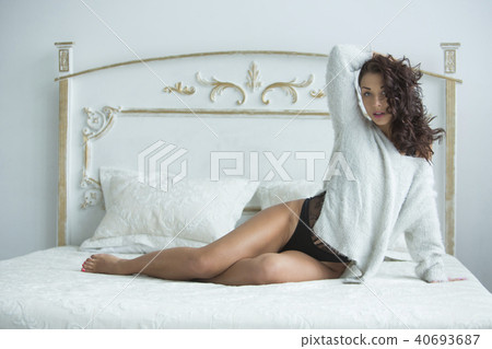 Beautiful young girl with curly hair lies in bed in the morning in a sexy suit and smiles. Morning Beautiful young girl with curly hair lies in bed in the morning in a sexy suit and smiles. Morning 40693687