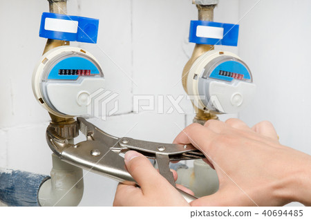 Technician installs a new water meter with wrench 40694485
