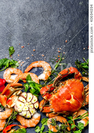 Fresh raw seafood - shrimps and crabs with herbs and spices on dark gray background. Copy space Fresh raw seafood - shrimps and crabs with herbs and spices on dark gray background. Copy space 40694894