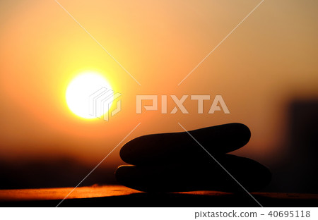 stack of pebble on yellow sun background 40695118