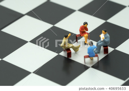 Miniature 4 people sitting on red staples placed  40695633