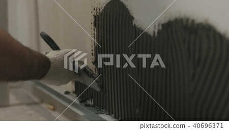 closeup worker applying concrete glue to wall before applying brick tile 40696371