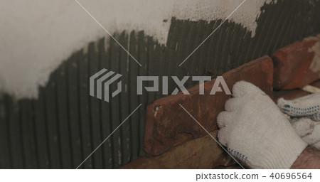 closeup worker applying brick cuts tile on the wall closeup worker applying brick cuts tile on the wall 40696564