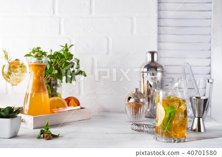 Orange lemonade in the decanter on a wooden tray, cocktail glass with ice, mint and ginger and Orange lemonade in the decanter on a wooden tray, cocktail glass with ice, mint and ginger and 40701580