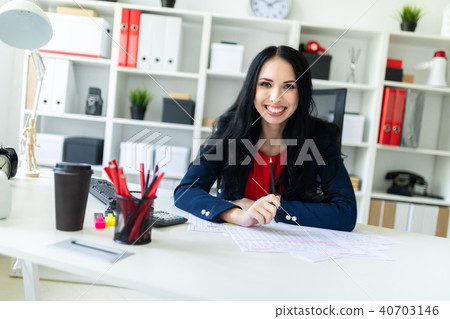 Beautiful young girl is working with documents in the office at the table and is holding a pencil in 40703146