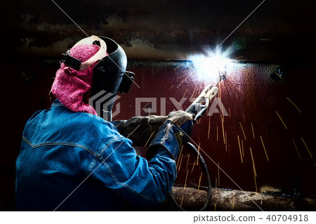 Steel welder with mask welding metal and sparks. 40704918