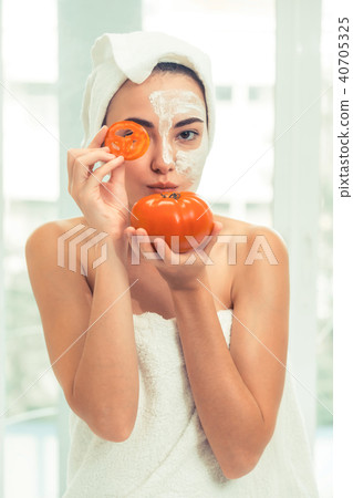 Woman get facial mask with tomato cream extract. 40705325
