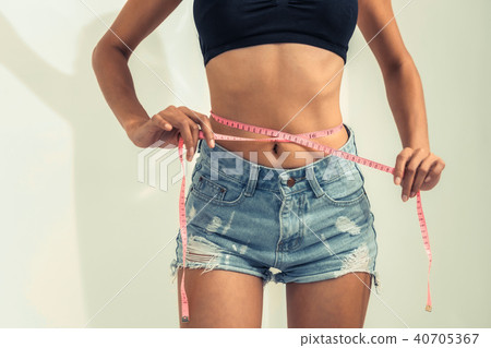 Slim woman measures her waist with measuring tape. Slim woman measures her waist with measuring tape. 40705367
