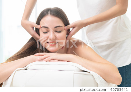Woman gets facial and head massage in luxury spa. Woman gets facial and head massage in luxury spa. 40705441