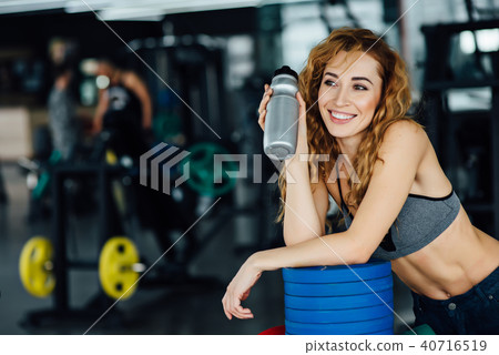 Young athletic woman drinking water in gym 40716519