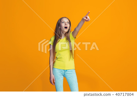 Beautiful teen girl looking suprised isolated on orange Beautiful teen girl looking suprised isolated on orange 40717804