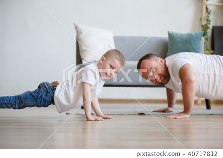 Image of young father and son pushing up on floor against sofa 40717812