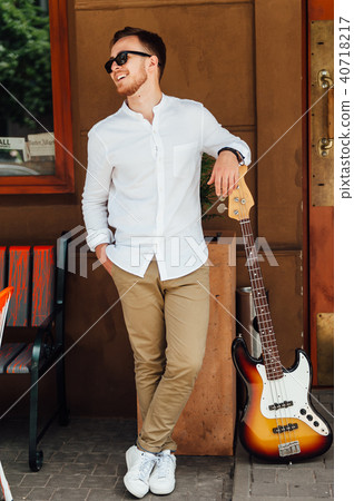 cheerful handsome guy stands near a guitar 40718217